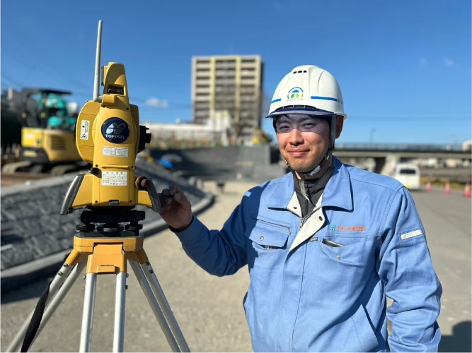 測量機器のそばで笑顔を見せるYさん